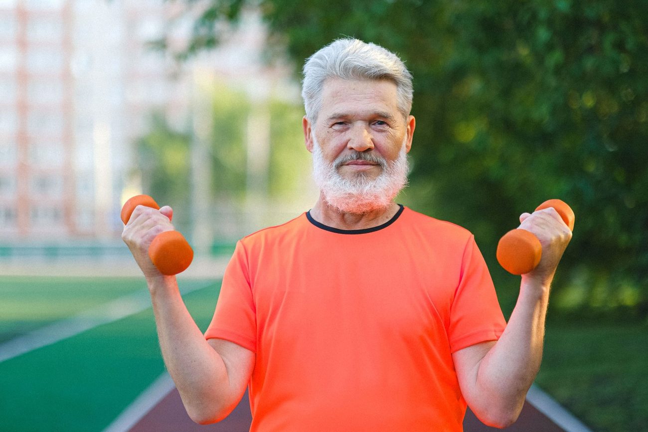 Man in orange shirt holding dumbells